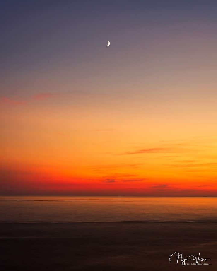 sunset over the Irish sea with the setting moon low in the sky