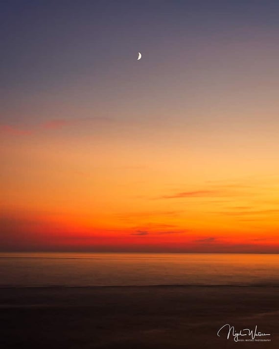 sunset over the Irish sea with the setting moon low in the sky