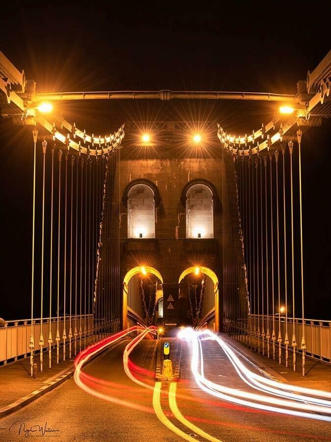 Photograph of vehicle light trails crossing the Menai Suspension Bridge in Wales.